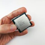 Close-up view of a hand holding an Intel Core i9 processor chip, showcasing technology details.