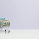 Shopping cart filled with cash on a plain background, ideal for finance and retail themes.