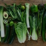 High-angle view of assorted fresh green vegetables arranged on a wooden table.