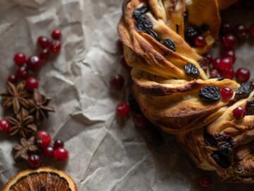 A rustic kringel bread with dried fruits and spices on parchment paper for a cozy setting.