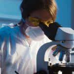 A female scientist examines a sample using a microscope in a laboratory setting.