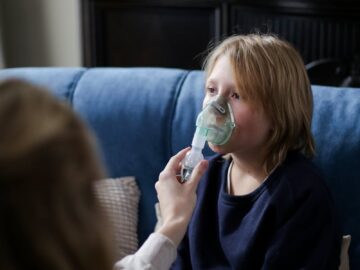 A young boy sits indoors receiving inhalation therapy, highlighting home healthcare.