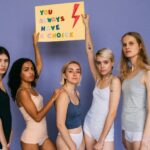 Group of diverse women standing together holding a motivational sign.