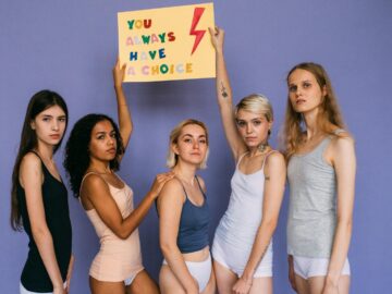 Group of diverse women standing together holding a motivational sign.