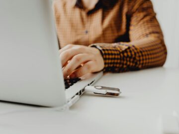 A person working on a laptop with a USB flash drive connected, representing technology and data storage.