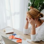 Woman stressed over financial receipts at a desk, dealing with expenses and calculations.