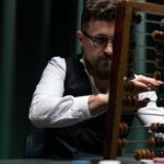 Businessman uses abacus with poker chips, capturing vintage calculation and gambling ambiance.