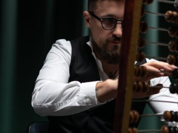 Businessman uses abacus with poker chips, capturing vintage calculation and gambling ambiance.