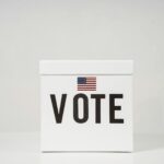 A minimalist ballot box with 'Vote' and an American flag, symbolizing elections.