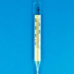 Close-up of a glass thermometer on a bright blue surface indicating temperature.