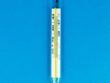 Close-up of a glass thermometer on a bright blue surface indicating temperature.