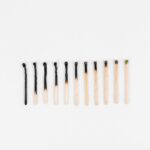 Conceptual image showing evolution of matchsticks from burnt to unlit arranged on white background.