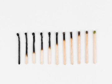 Conceptual image showing evolution of matchsticks from burnt to unlit arranged on white background.