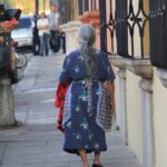 woman in red and black dress walking on sidewalk during daytime