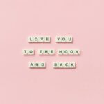 Letter tiles spelling 'Love You to the Moon and Back' on a pink background.
