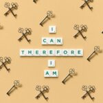 Inspirational phrase made from tiles surrounded by decorative keys on a beige background.