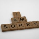 Wooden Scrabble tiles arranged to say 'I Am Sorry' on a clean white background, conveying a message of apology.