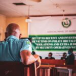 A man in uniform attending a judicial panel meeting indoors.