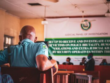 A man in uniform attending a judicial panel meeting indoors.