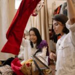 Two women enjoying a fun shopping day at a thrift clothing store.