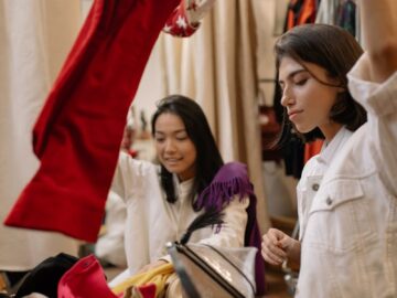 Two women enjoying a fun shopping day at a thrift clothing store.