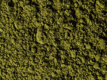 Closeup view of coarse green matcha powder texture, ideal for backgrounds and culinary themes.