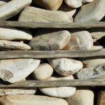 A vertical arrangement of smooth stones secured by wooden slats in natural light.