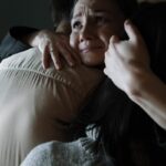 A sincere moment of emotional support as two people embrace tenderly in a dimly lit room.