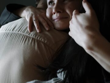 A sincere moment of emotional support as two people embrace tenderly in a dimly lit room.