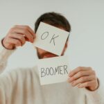 A person holding two cards with 'OK Boomer' written in bold text.