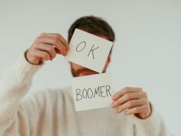 A person holding two cards with 'OK Boomer' written in bold text.