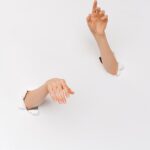 An artistic shot of two hands emerging from a white wall, symbolizing creativity and expression.