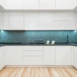 Interior of white modern kitchen with minimalist design of white cabinets blue backsplash and black built in appliances