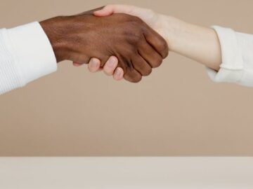 Close-up of a diverse handshake symbolizing unity and cooperation on a neutral background.