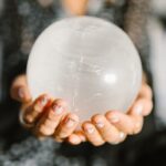 Close-up of hands holding a clear crystal ball, ideal for spiritual or metaphysical themes.