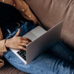 Close-up of a person using a laptop while lounging on a sofa, embodying a relaxed work-from-home vibe.
