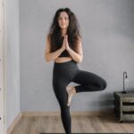 A woman practicing yoga indoors, focusing on balance and mindfulness.