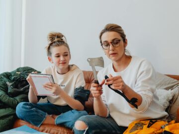 Mom and daughter bonding over learning tools on the couch indoors.