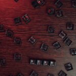 Scattered keyboard keys spelling 'SCAM' on a red-lit wooden surface, symbolizing online fraud.