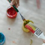 Close-up of hands using vibrant paints and brushes, fostering creativity.