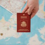 A hand holding a Russian passport above a travel-themed map, capturing world travel concepts.