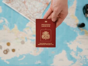 A hand holding a Russian passport above a travel-themed map, capturing world travel concepts.