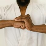 Close-up of a martial artist's hands clasped in a traditional martial arts gesture.