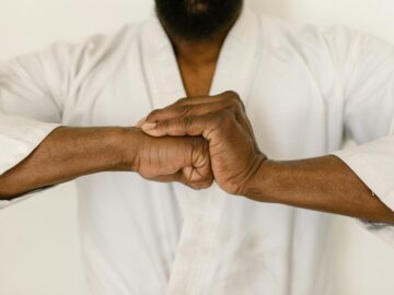 Close-up of a martial artist's hands clasped in a traditional martial arts gesture.