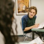 Students engaging in discussion during an exam in a classroom, conveying themes of education and collaboration.
