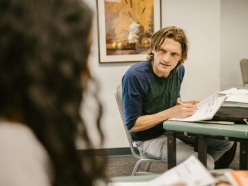 Students engaging in discussion during an exam in a classroom, conveying themes of education and collaboration.
