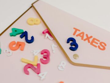 Bright plastic numbers scattered over a tax envelope, symbolizing accounting and finance concepts.