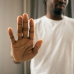 Close-up of a man with a hand gesture expressing stop or refusal indoors