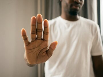 Close-up of a man with a hand gesture expressing stop or refusal indoors