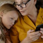 Senior woman and young girl enjoying time together, bonding over a smartphone indoors.